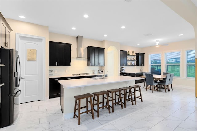 16696 Otterchase Ln, Winter Garden, FL 34787 - kitchen featuring wall chimney range hood, fridge with ice dispenser, a sink, cooktop, and light marble finish floors