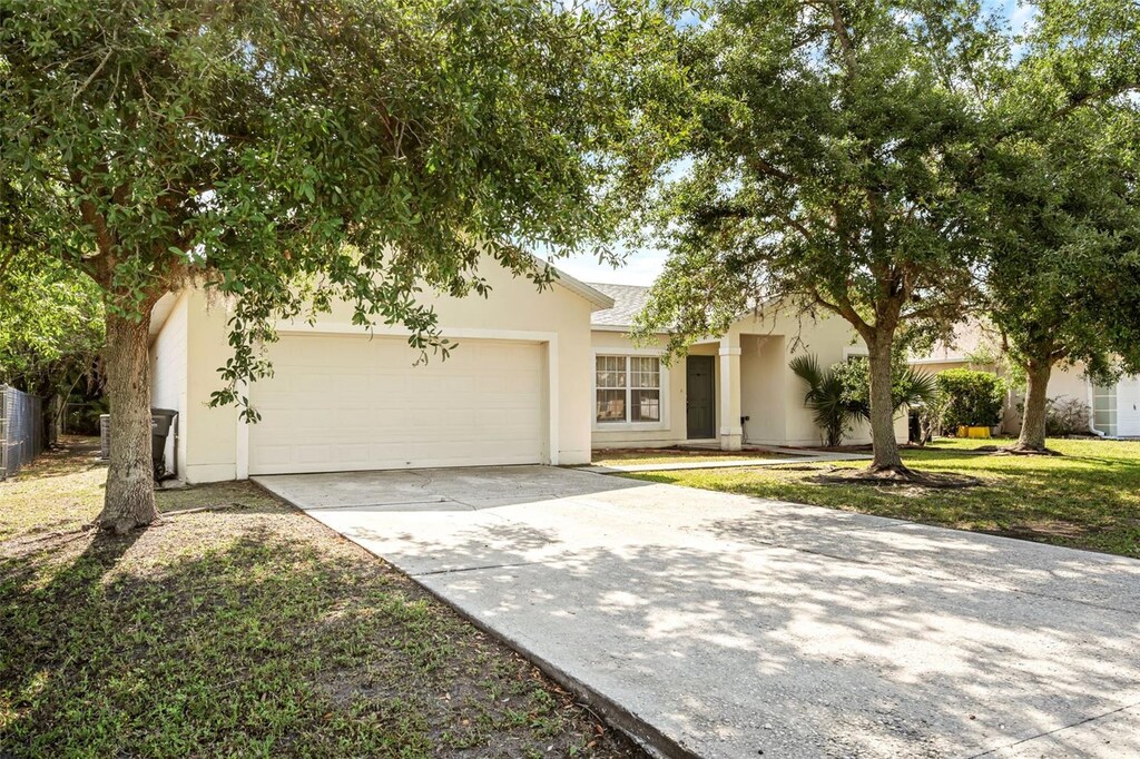672 Reindeer Dr, Kissimmee, FL 34759 - view of front facade featuring stucco siding, an attached garage, concrete driveway, and fence