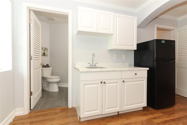 656 Lake Charm Dr, Oviedo, FL 32765 - kitchen featuring a sink, freestanding refrigerator, ornamental molding, arched walkways, and white cabinetry