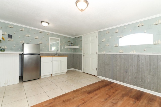 656 Lake Charm Dr, Oviedo, FL 32765 - kitchen featuring freestanding refrigerator, a sink, wainscoting, crown molding, and white cabinets