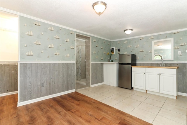 656 Lake Charm Dr, Oviedo, FL 32765 - kitchen featuring freestanding refrigerator, a wainscoted wall, crown molding, light wood-style floors, and white cabinets