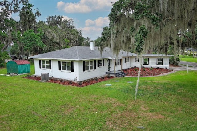 656 Lake Charm Dr, Oviedo, FL 32765 - rear view of property with a storage shed, central air condition unit, an outbuilding, a lawn, and a shingled roof