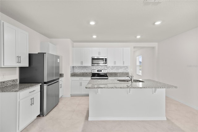 280 Caryota Ct, New Smyrna Beach, FL 32168 - kitchen featuring stainless steel appliances, a sink, light stone countertops, white cabinetry, and a breakfast bar area