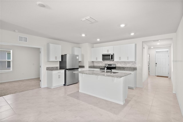 280 Caryota Ct, New Smyrna Beach, FL 32168 - kitchen with stainless steel appliances, a sink, an island with sink, white cabinets, and a kitchen breakfast bar