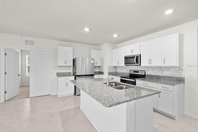 280 Caryota Ct, New Smyrna Beach, FL 32168 - kitchen with appliances with stainless steel finishes, a sink, tasteful backsplash, an island with sink, and white cabinets