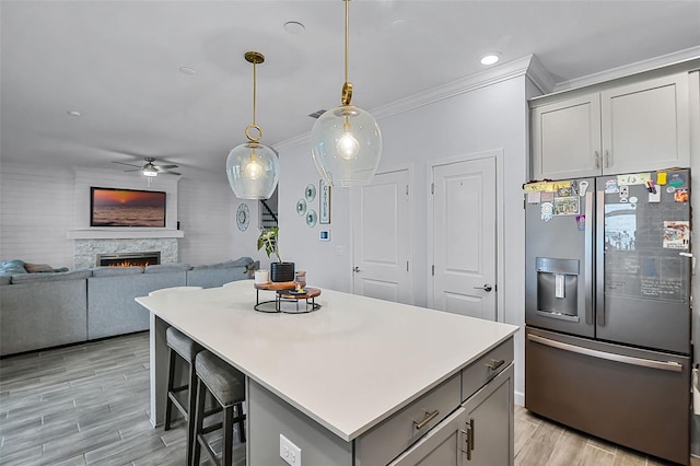 1123 Dora Parc Ln, Mount Dora, FL 32757 - kitchen featuring stainless steel fridge, gray cabinetry, ceiling fan, ornamental molding, and a stone fireplace