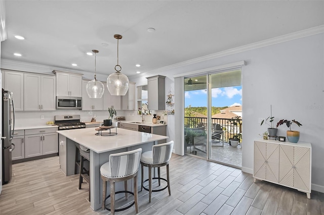 1123 Dora Parc Ln, Mount Dora, FL 32757 - kitchen with appliances with stainless steel finishes, gray cabinets, ornamental molding, a kitchen bar, and light wood-style flooring