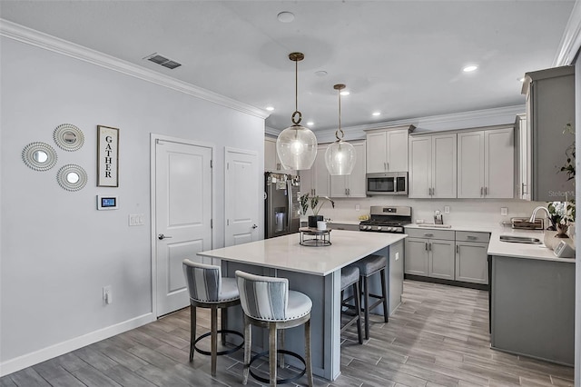 1123 Dora Parc Ln, Mount Dora, FL 32757 - kitchen featuring stainless steel appliances, a breakfast bar area, a sink, gray cabinetry, and crown molding