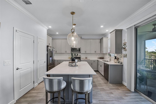 1123 Dora Parc Ln, Mount Dora, FL 32757 - kitchen featuring appliances with stainless steel finishes, gray cabinetry, crown molding, a center island, and a kitchen breakfast bar