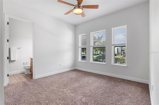 8692 Tavistock Lakes Blvd, Orlando, FL 32827 - unfurnished bedroom featuring light colored carpet, connected bathroom, ceiling fan, and light tile patterned floors