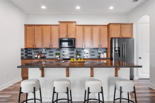 8692 Tavistock Lakes Blvd, Orlando, FL 32827 - kitchen with appliances with stainless steel finishes, dark wood-type flooring, backsplash, a center island with sink, and recessed lighting
