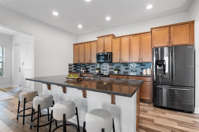 8692 Tavistock Lakes Blvd, Orlando, FL 32827 - kitchen with appliances with stainless steel finishes, brown cabinetry, light wood finished floors, tasteful backsplash, and recessed lighting