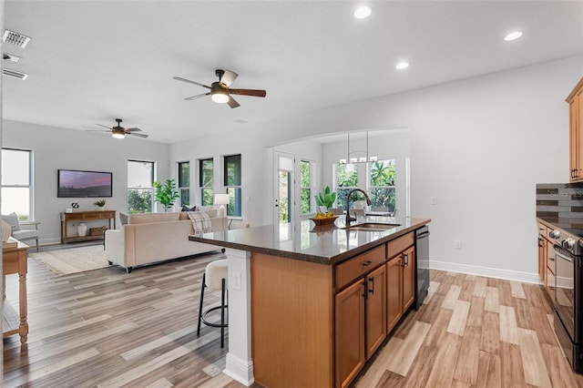 8692 Tavistock Lakes Blvd, Orlando, FL 32827 - kitchen featuring light wood-style floors, range with electric cooktop, a kitchen breakfast bar, a ceiling fan, and brown cabinets