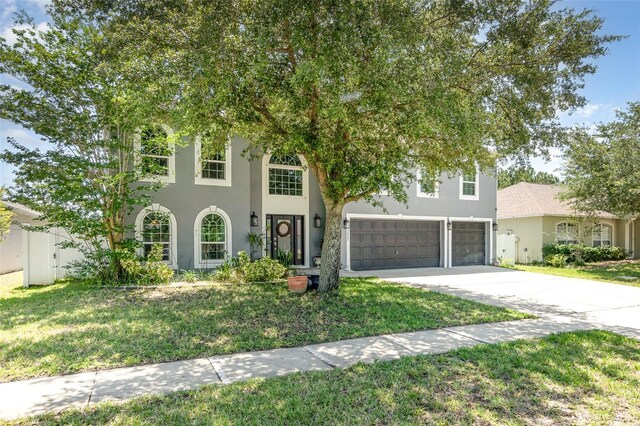 3063 Mandolin Dr, Kissimmee, FL 34744 - view of front facade featuring a garage, concrete driveway, a front lawn, and stucco siding