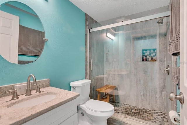 full bath with toilet, a shower stall, vanity, a textured ceiling, and a textured wall
