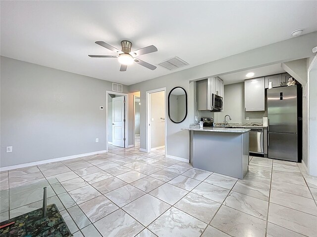 9506 Number Two Rd, Howey In The Hills, FL 34737 - kitchen with appliances with stainless steel finishes, light marble finish floors, a ceiling fan, baseboards, and a peninsula