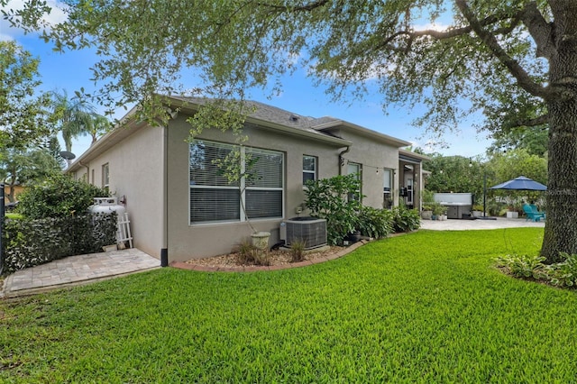 back of property featuring stucco siding, a patio, a yard, and central air condition unit
