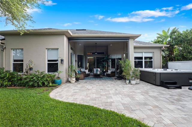 back of property featuring a hot tub, a patio area, an outdoor hangout area, stucco siding, and a yard