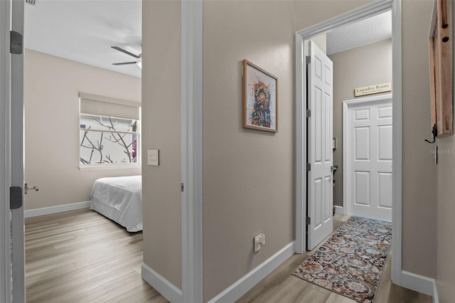 corridor featuring light wood-type flooring and baseboards