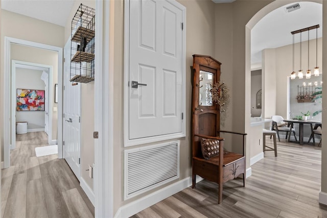 foyer featuring light wood-style floors, arched walkways, and baseboards