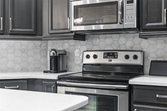 kitchen with stainless steel appliances, tasteful backsplash, light countertops, and dark cabinets