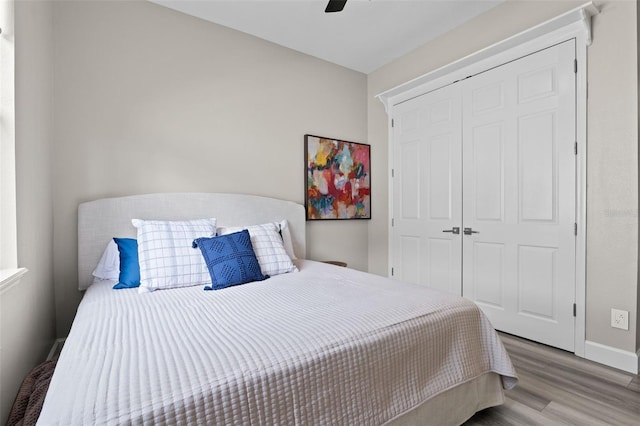bedroom featuring wood finished floors, a closet, baseboards, and ceiling fan