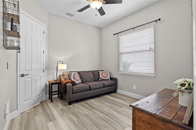 living room with light wood-style flooring, baseboards, and ceiling fan
