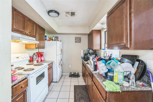 3711 Shady Grove Cir, Orlando, FL 32810 - kitchen with white appliances, under cabinet range hood, light tile patterned floors, and brown cabinetry