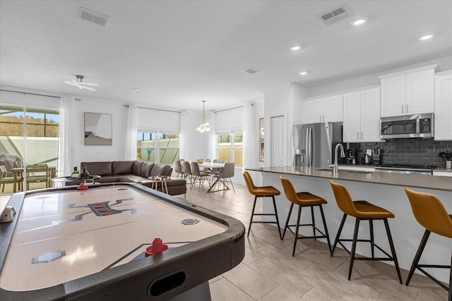 recreation room with plenty of natural light, a sink, recessed lighting, and light tile patterned floors