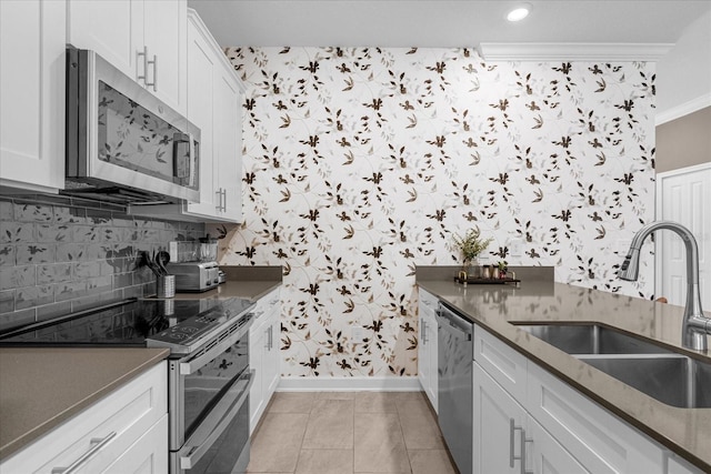 kitchen with stainless steel appliances, a sink, wallpapered walls, dark countertops, and baseboards