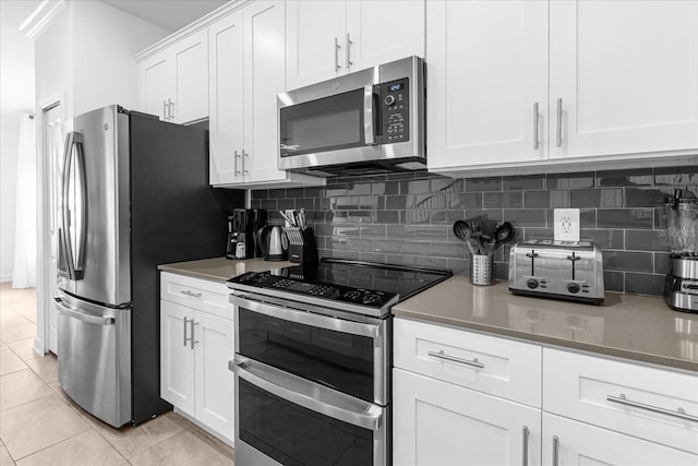 kitchen with stainless steel appliances, tasteful backsplash, white cabinets, and light tile patterned floors