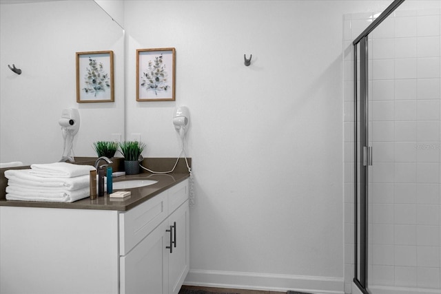 full bath with a tile shower, vanity, and baseboards