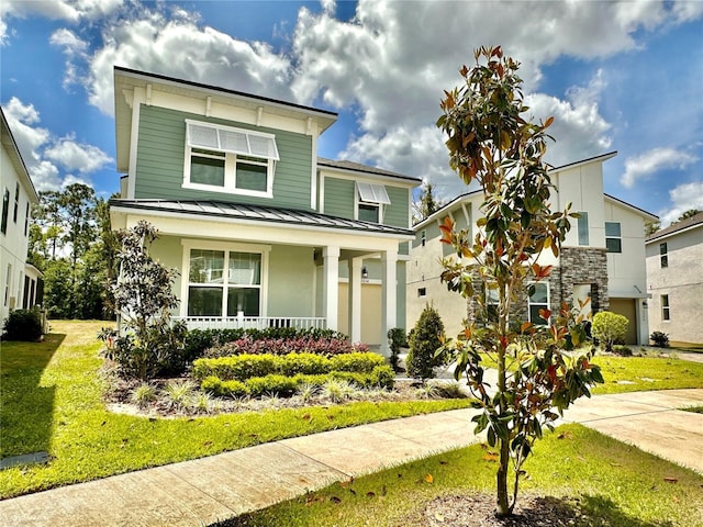 view of front of property with a standing seam roof, a porch, metal roof, and a front lawn