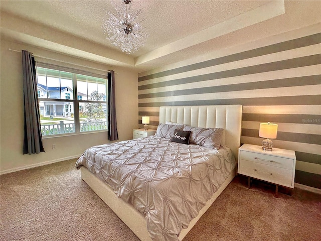 carpeted bedroom featuring a textured ceiling, baseboards, and a tray ceiling