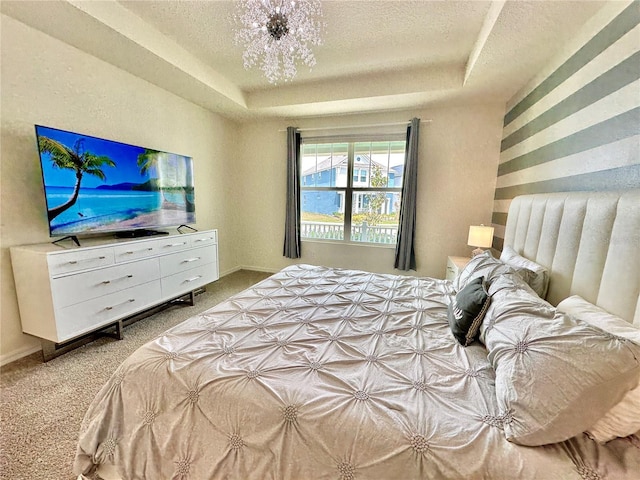 bedroom with a raised ceiling, carpet flooring, and a textured ceiling