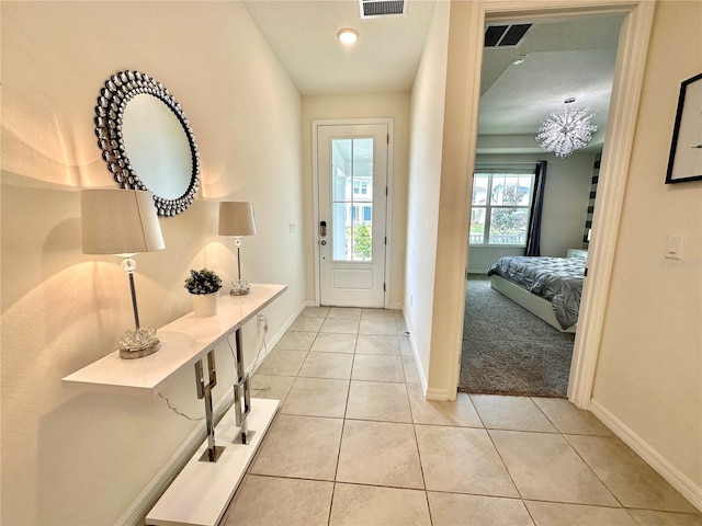 doorway with light tile patterned floors, baseboards, and a chandelier