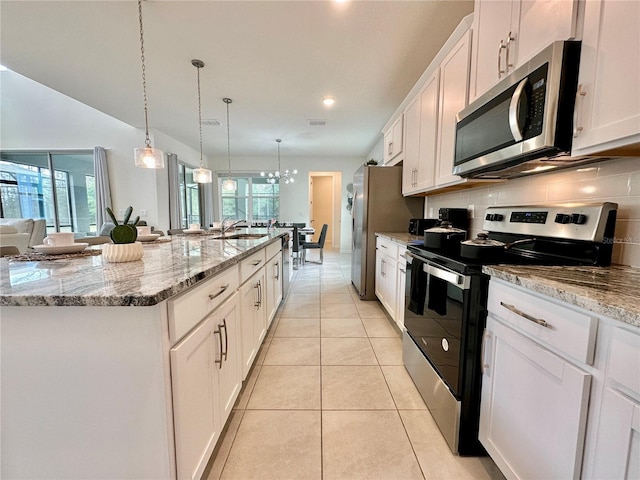 kitchen featuring stainless steel appliances, a sink, a large island, white cabinets, and tasteful backsplash