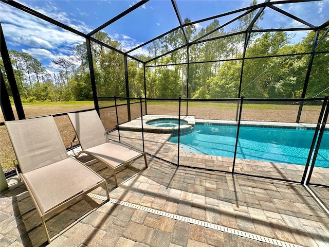 view of pool featuring a patio area, a pool with connected hot tub, a lanai, and view of wooded area
