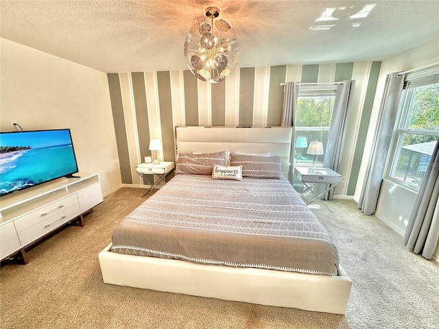 carpeted bedroom with wallpapered walls, baseboards, a textured ceiling, and a chandelier