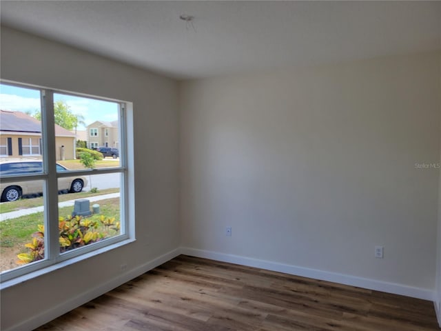 spare room featuring plenty of natural light, wood finished floors, and baseboards