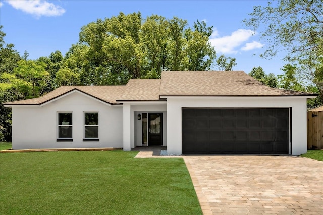 view of front of house featuring an attached garage, a shingled roof, a front lawn, driveway, and stucco siding