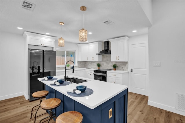 kitchen with wall chimney exhaust hood, a sink, black appliances, light wood-style flooring, and recessed lighting
