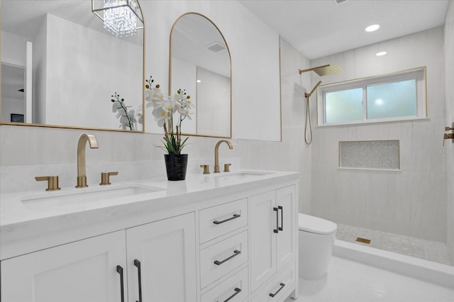 full bath featuring tiled shower, double vanity, and toilet