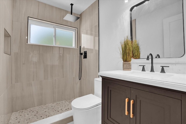 bathroom featuring toilet, vanity, and a tile shower