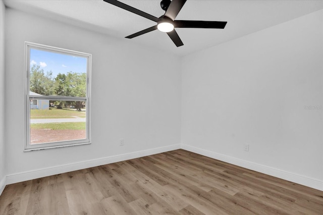 empty room featuring wood finished floors, a ceiling fan, and baseboards