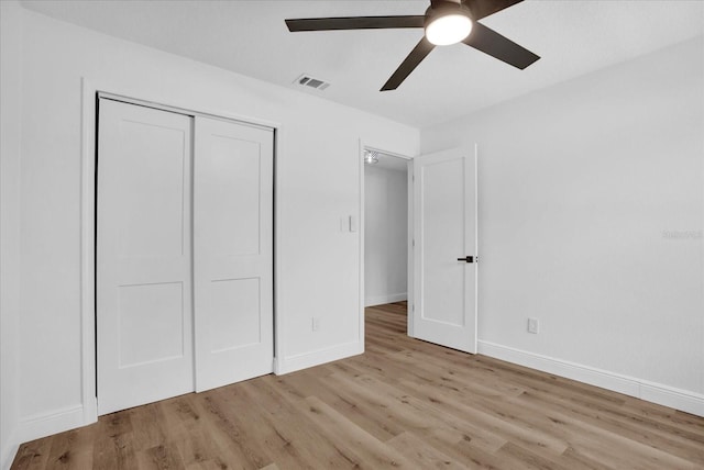 unfurnished bedroom with wood finished floors, a closet, baseboards, and ceiling fan