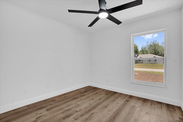 empty room featuring wood finished floors, baseboards, and ceiling fan