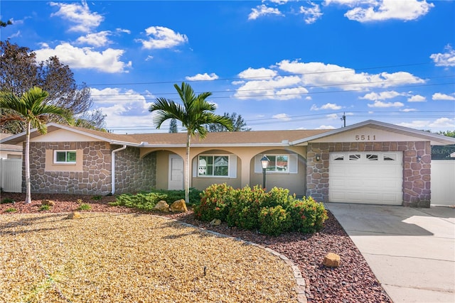 ranch-style home with stone siding, driveway, a garage, and fence