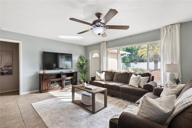 living area featuring ceiling fan, baseboards, and light tile patterned floors