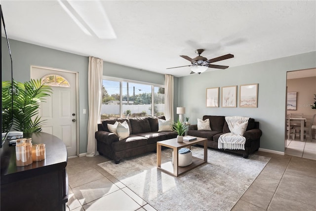 living room featuring healthy amount of natural light, ceiling fan, light tile patterned floors, and baseboards